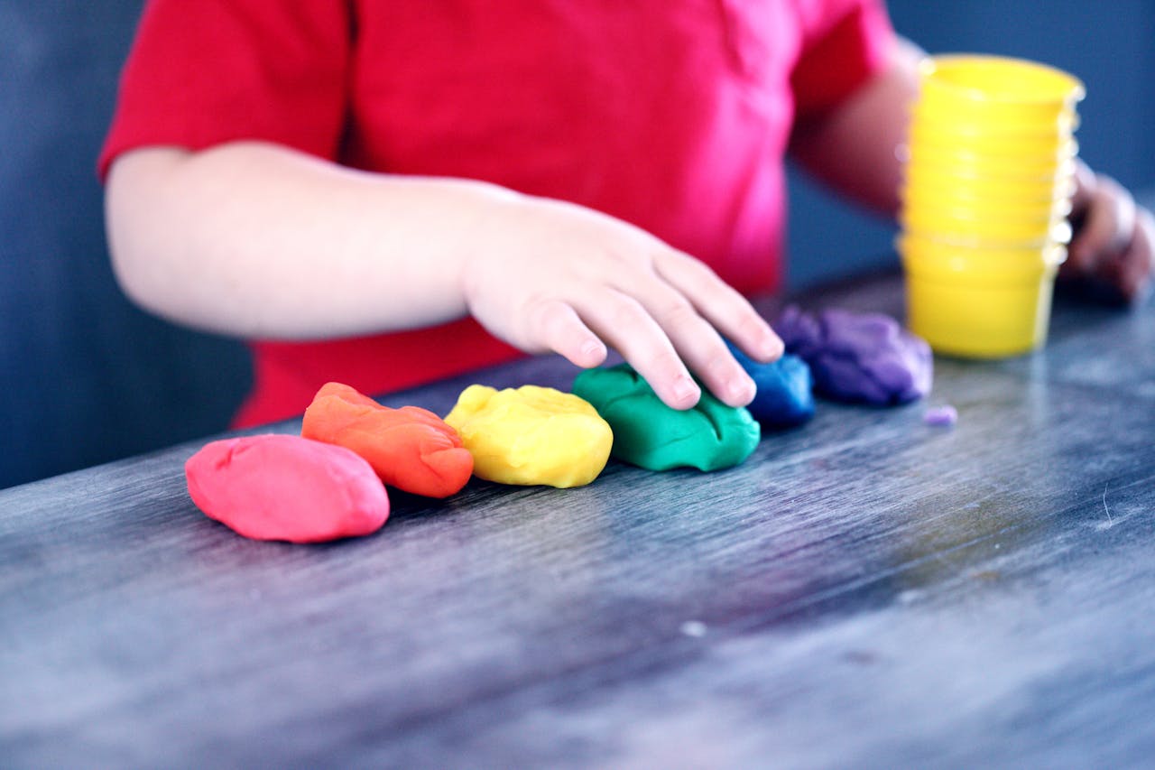 Mastering the First Impression: Your intriguing post title goes here A young child with rainbow-colored modeling clay and stacking cups on a table indoors.