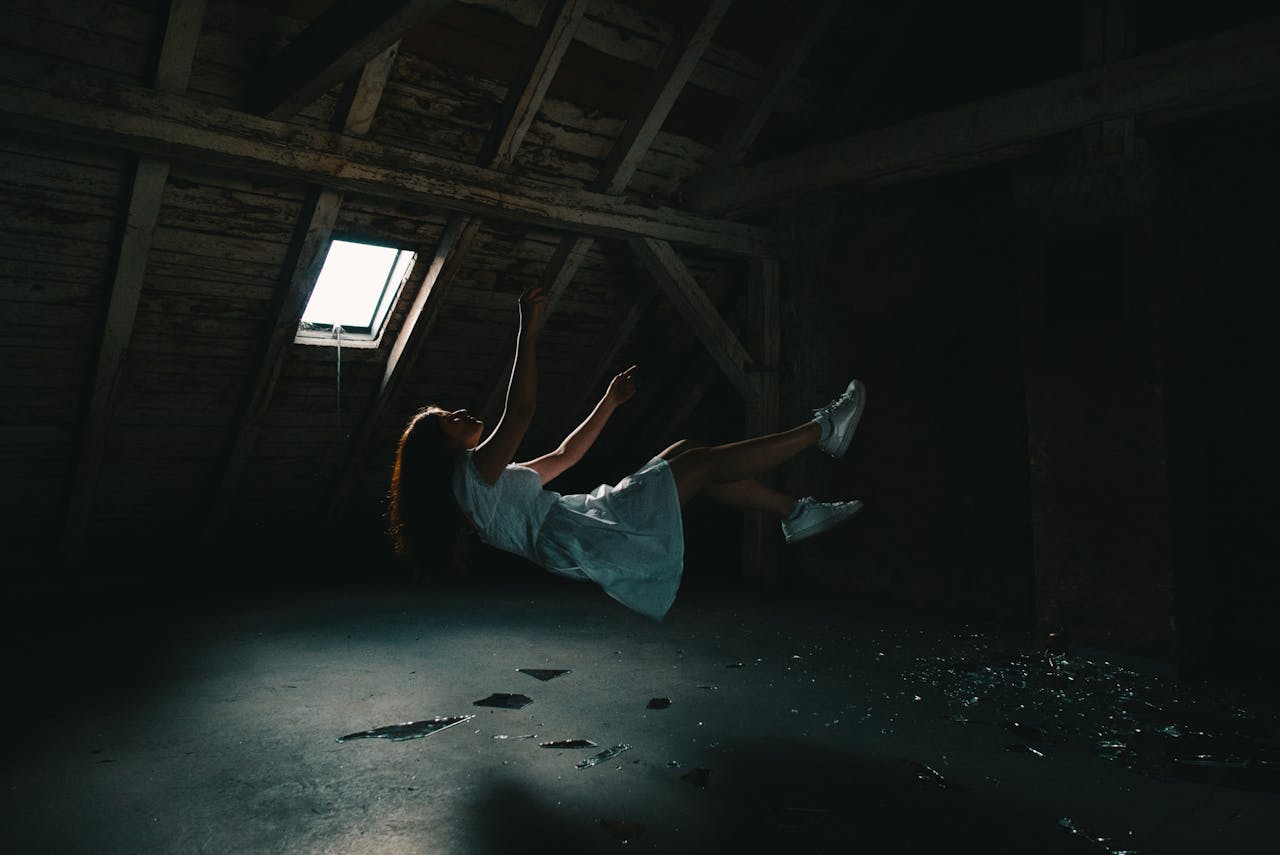 services-01 A surreal photograph of a woman in a white dress floating in an abandoned attic, capturing a sense of mystery.