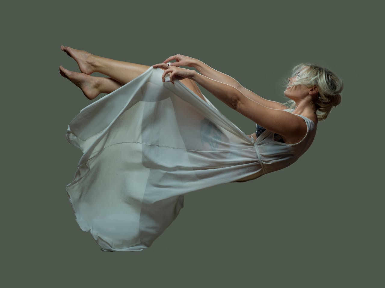 services-img Elegant woman floating mid-air in a sheer dress against a solid background.