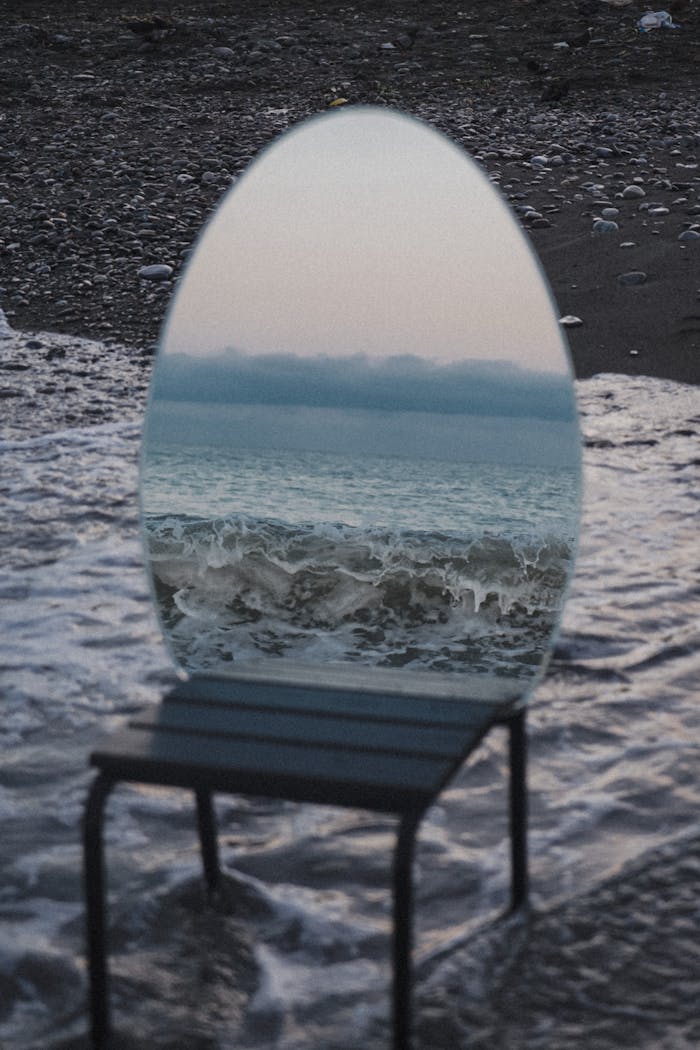 services-02 An artistic mirror reflecting ocean waves on the beach, creating a surreal and enchanting scene.